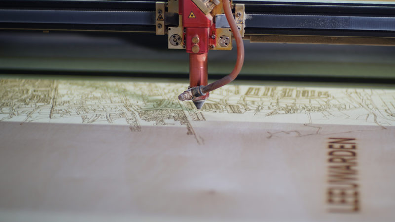 Een werkende original lasermachine die bezig is met het maken van een houten citymap.